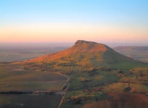 A picture of Roseberry Topping being lit by the early morning sun with a clear blue sky